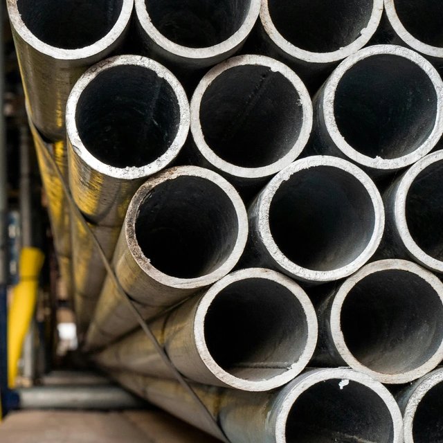 Etupuolelta kuvattu suurten metalliputkien pino, joita käytetään yleisesti putkistoissa, rakentamisessa tai teollisuudessa.
